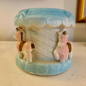 May include: A blue and white ceramic carousel horse planter with two horses, one pink and one brown, with white stripes.