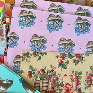 Peut inclure: Un ensemble de papiers d'emballage color&eacute;s avec diff&eacute;rents motifs. La feuille sup&eacute;rieure pr&eacute;sente un fond rose avec un motif r&eacute;p&eacute;t&eacute; de champignons bruns et de fleurs bleues. La deuxi&egrave;me feuille a un fond jaune avec un motif r&eacute;p&eacute;t&eacute; de fraises rouges et de feuilles vertes. La troisi&egrave;me feuille a un fond bleu clair avec un motif r&eacute;p&eacute;t&eacute; de points color&eacute;s.
