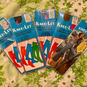 May include: A collection of vintage Knee-Let knee-high hose packages. The packages are blue with the text "Knee-Let" and "One Size Fits All Knee High Hose." The packages feature illustrations of legs wearing red, green, and blue hose.
