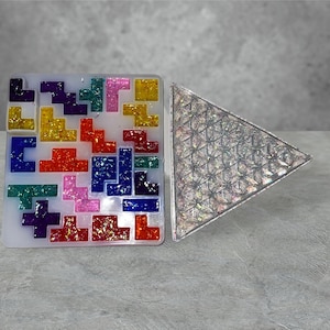 May include: A clear silicone mold with a colorful Tetris-like design and a clear triangle mold with a geometric pattern.
