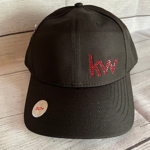 May include: Black baseball cap with a red rhinestone "KW" logo on the front. The cap has a curved brim and a white tag with "50+" printed on it.