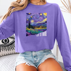 May include: A long-sleeved, purple sweatshirt featuring a colorful print of Van Gogh's "Starry Night" painting. The text "LET IT GOGH" is printed below the artwork. The sweatshirt is made of a soft material.
