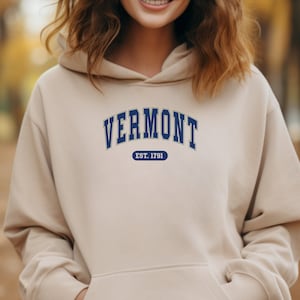 May include: A beige hoodie with a blue and green "VERMONT EST. 1791" graphic on the front.