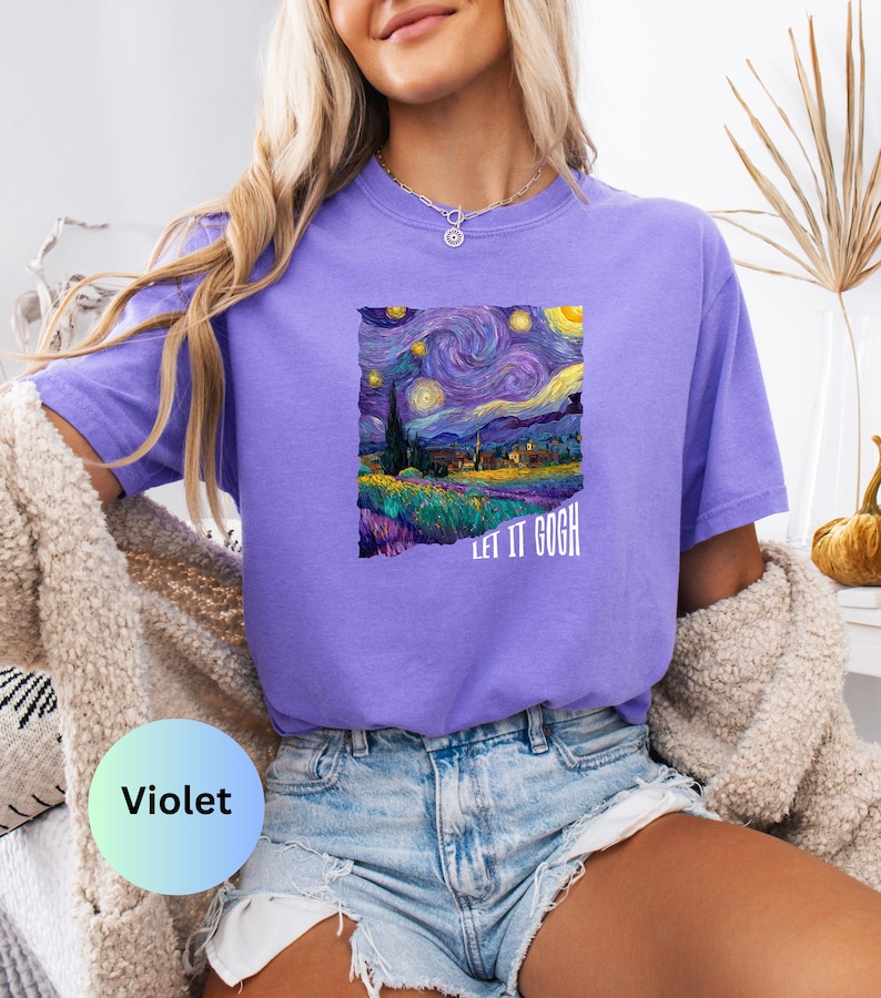 K&ouml;nnte beinhalten: Violettes T-Shirt mit einem Druck von Van Goghs Gem&auml;lde "Sternennacht". Das Kunstwerk zeigt einen wirbelnden Nachthimmel, ein Dorf und den Text "LET IT GOGH". Das Shirt wird mit Jeansshorts kombiniert.