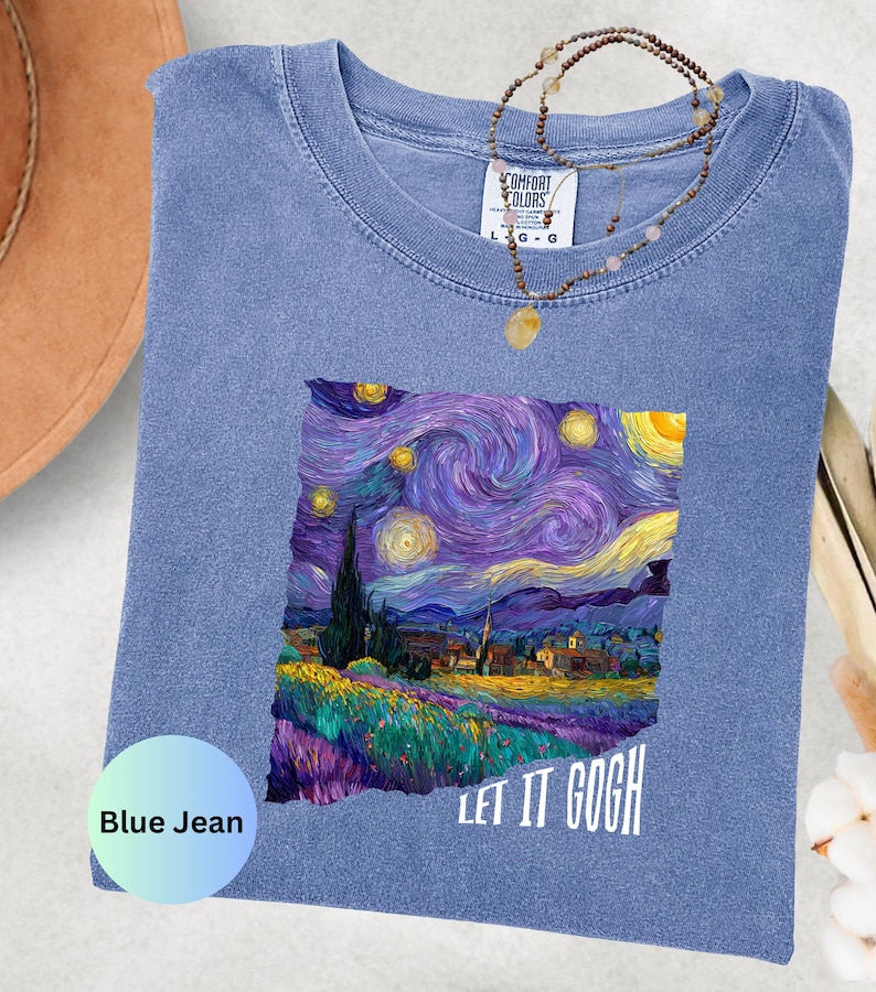 K&ouml;nnte beinhalten: Blaues Jeans-T-Shirt mit einem farbenfrohen Druck von Van Goghs Gem&auml;lde "Sternennacht". Der Schriftzug "LET IT GOGH" ist wei&szlig;. Eine Halskette mit Anh&auml;nger liegt auf dem T-Shirt.