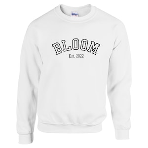 May include: White sweatshirt with black text that reads "BLOOM Est. 2022" in an arched font.