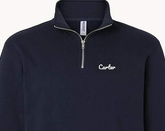 May include: A navy blue quarter-zip sweatshirt featuring a silver-toned metal zipper at the collar and the name Carter embroidered in white script lettering on the upper left chest area of the garment.