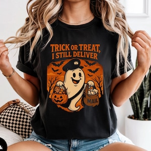 May include: Black t-shirt with a Halloween-themed graphic. The design features a cartoon ghost wearing a mail carrier hat, holding a pumpkin and a mail bag. The text "Trick or Treat, I Still Deliver" is printed above the graphic.