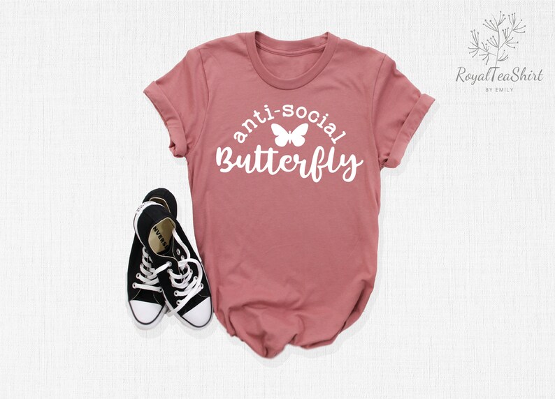 May include: A dusty rose t-shirt with the text "anti-social butterfly" in white lettering with a white butterfly graphic.