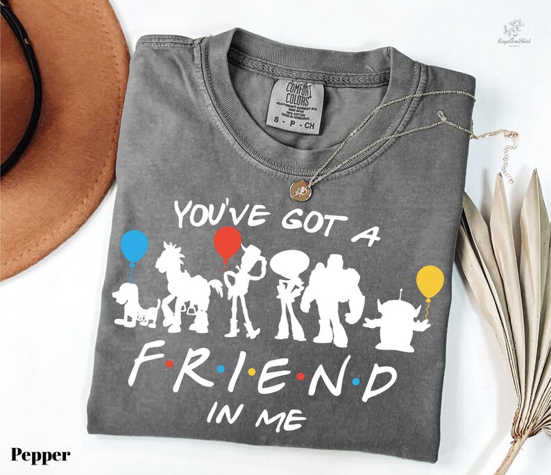 A gray t-shirt with a printed design of various cartoon characters and the text "You've Got a Friend in Me" printed on it.