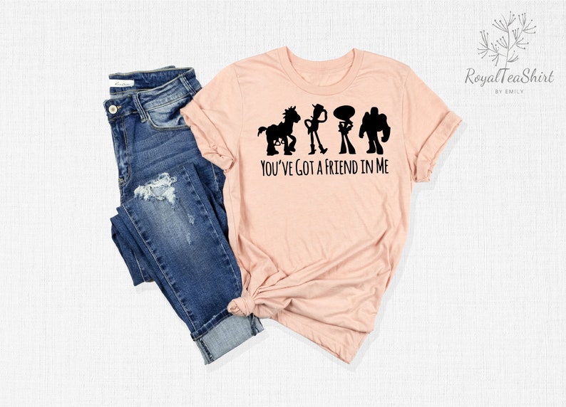 May include: A pink t-shirt featuring a black silhouette of the Toy Story characters Woody, Buzz Lightyear, and Bullseye, with the text "You've Got a Friend in Me".
