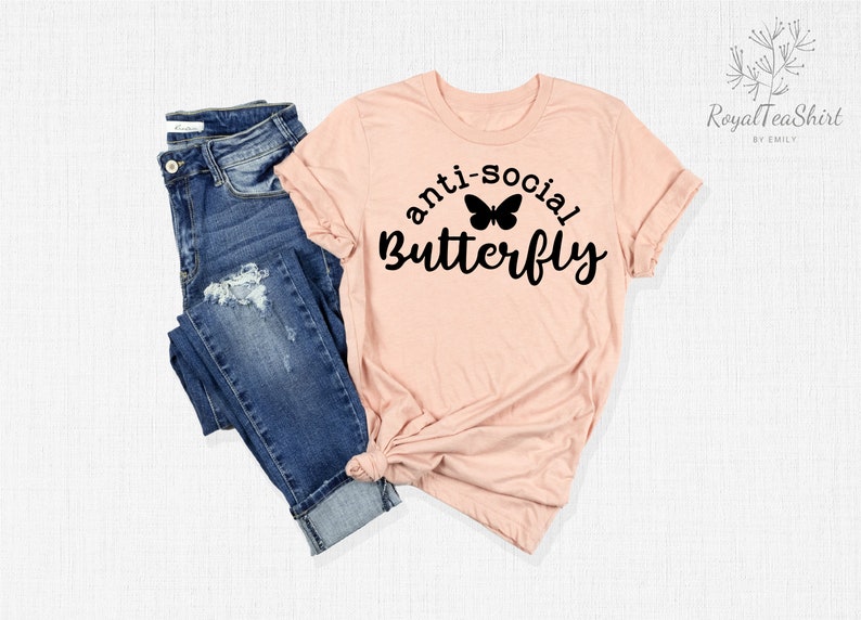 May include: A pink t-shirt with the text "anti-social butterfly" in black lettering and a black butterfly graphic.