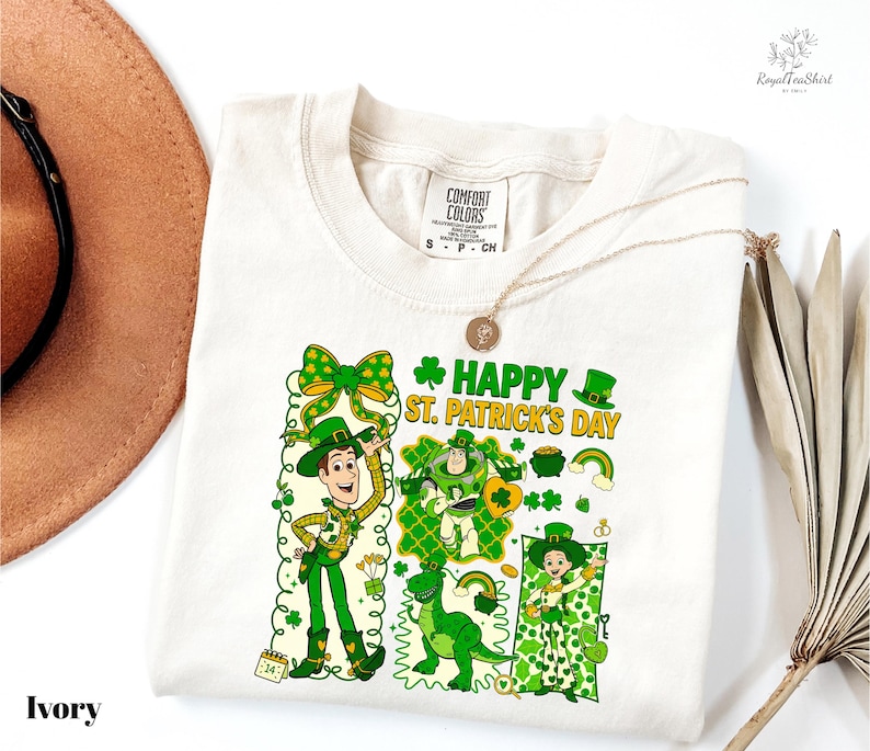 A white t-shirt with a cartoon design of St. Patrick's Day characters, including a man, a woman, and a child, along with various St. Patrick's Day symbols and text.