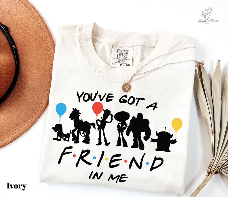A white t-shirt with a graphic design featuring silhouettes of characters from the TV show Toy Story, along with the text "You've Got a Friend in Me".