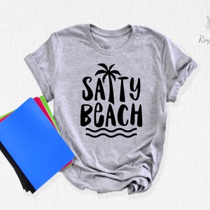 May include: A gray t-shirt with a black graphic that says "SAPPY BEACH" with a palm tree and waves.