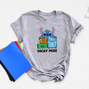 May include: Gray t-shirt with a blue cartoon character holding suitcases and the text "Vacay Mode".