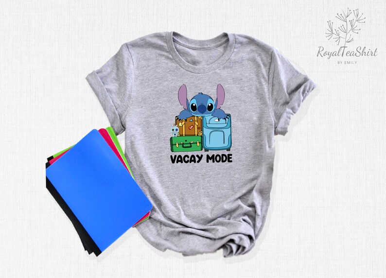 May include: Gray t-shirt with a blue cartoon character holding suitcases and the text "Vacay Mode".