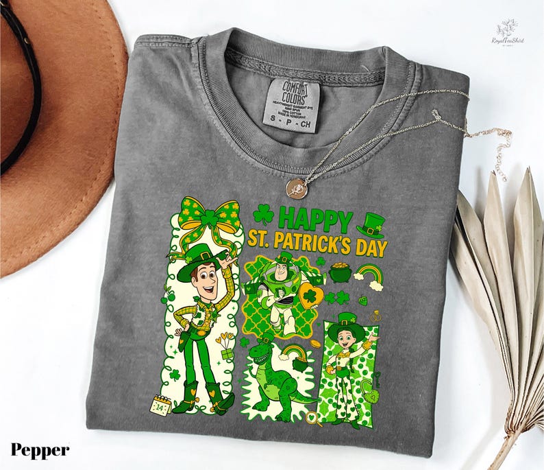 A gray t-shirt with a cartoon character design and text related to St. Patrick's Day, along with a necklace and a hat.