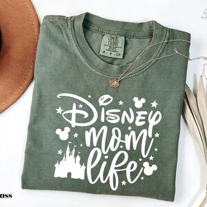 A green t-shirt with white text and graphics, including a castle and stars, is displayed on a white background.