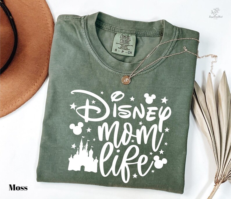A green t-shirt with white text and graphics, including a castle and stars, is displayed on a white background.