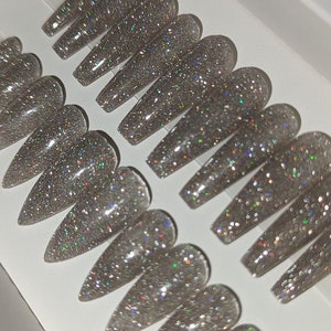 May include: A set of 10 silver glitter long coffin-shaped false nails.