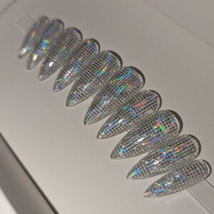May include: Set of ten iridescent silver stiletto false nails with a grid pattern.