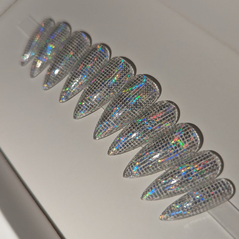 May include: Set of ten iridescent silver stiletto false nails with a grid pattern.