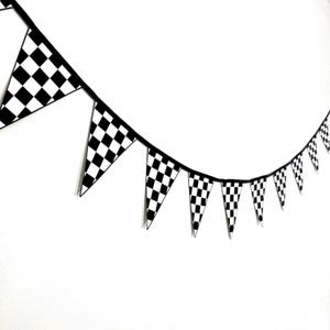 May include: Black and white checkered flag bunting. The bunting is made of paper and is strung together with a black string. The bunting is perfect for a race-themed party.