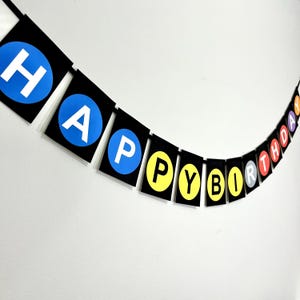 May include: A black and white banner with the words "Happy Birthday" spelled out in colorful circles. Each letter is on a separate circle with a black background.