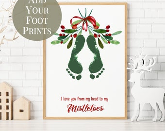 May include: A framed print with green footprints forming mistletoe, adorned with a red bow and berries. The text says "I love you from my head to my Mistletoes." A circular graphic says "Add Your Foot Prints."