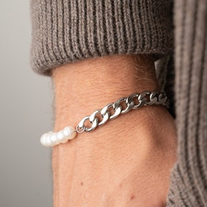 May include: A silver chain bracelet with a row of white pearls.