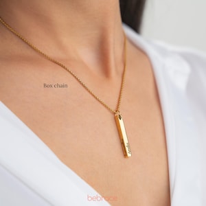 Op de afbeelding: Een gouden ketting met een boxketting en een verticale staafhanger gegraveerd met de naam "Amelia".