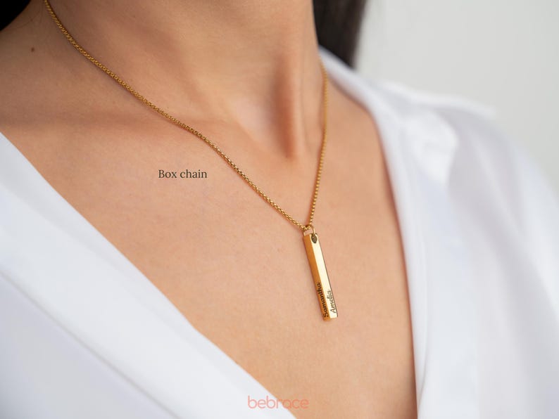 Op de afbeelding: Een gouden ketting met een boxketting en een verticale staafhanger gegraveerd met de naam "Amelia".