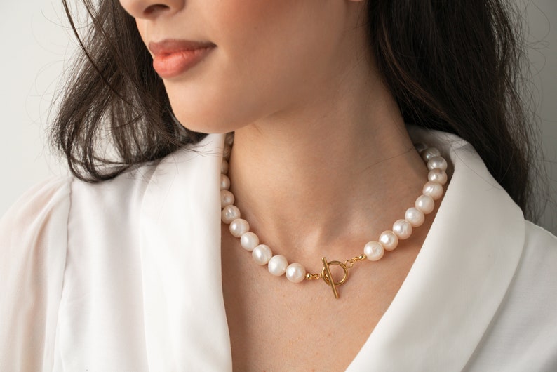 large pearl necklace on the model made with cultured freshwater 12mm round white pearls, includes stainless steel toggle clasp