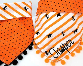 May include: Two pet bandanas featuring Halloween themes. One is orange with black polka dots and black pom-poms. The other is white with orange diagonal stripes, black cat silhouettes, an orange polka dot top border, and the name Jasper embroidered.