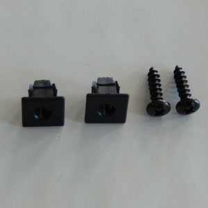 May include: Two black plastic clips with a square base and a central hole, paired with two black screws. The screws have a Phillips head and a spiral design. The items are likely hardware components.