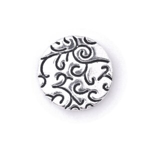 May include: A silver charm with a circular design featuring a black swirl pattern.