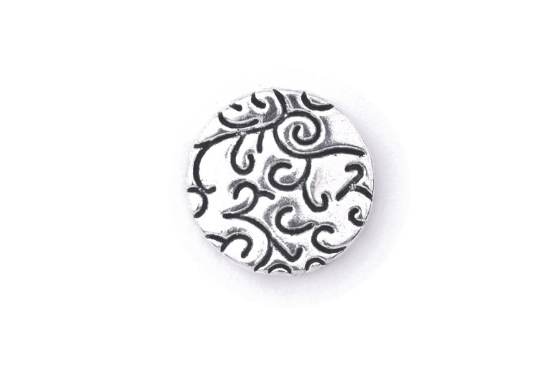 May include: A silver charm with a circular design featuring a black swirl pattern.