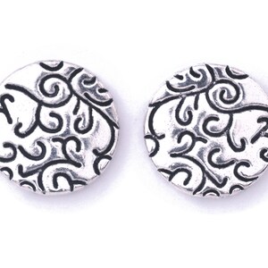 May include: A pair of silver earrings with a circular design featuring a black swirl pattern.