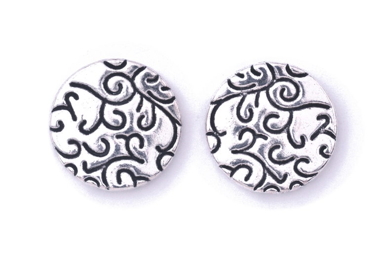 May include: A pair of silver earrings with a circular design featuring a black swirl pattern.