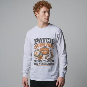 Pode incluir: Uma t-shirt branca de manga comprida com um gráfico de uma abóbora zangada, uma chávena entornada e folhas de outono. O texto diz PATCH SURVIVOR ONE MORE TANTRUM AND WE'RE LEAVING. O design inclui pegadas castanhas e detalhes em laranja.