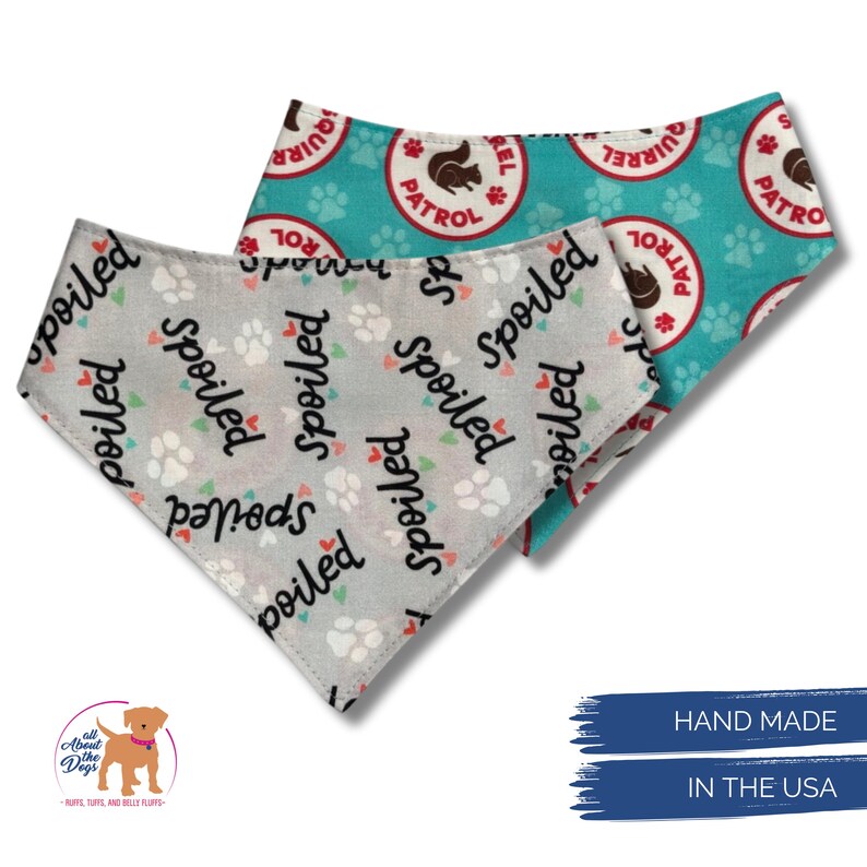 May include: Two dog bandanas. One is light gray with paw prints and the word "spoiled" in black. The other is turquoise with paw prints and a "Squirrel Patrol" logo. The bandanas are handmade in the USA.