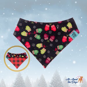 May include: A black dog bandana with a festive pattern of red and green mittens and white snowflakes. A smaller, inset image shows a reversible bandana with a red and black plaid pattern. The bandana has a tag that says "All About the Dogs".