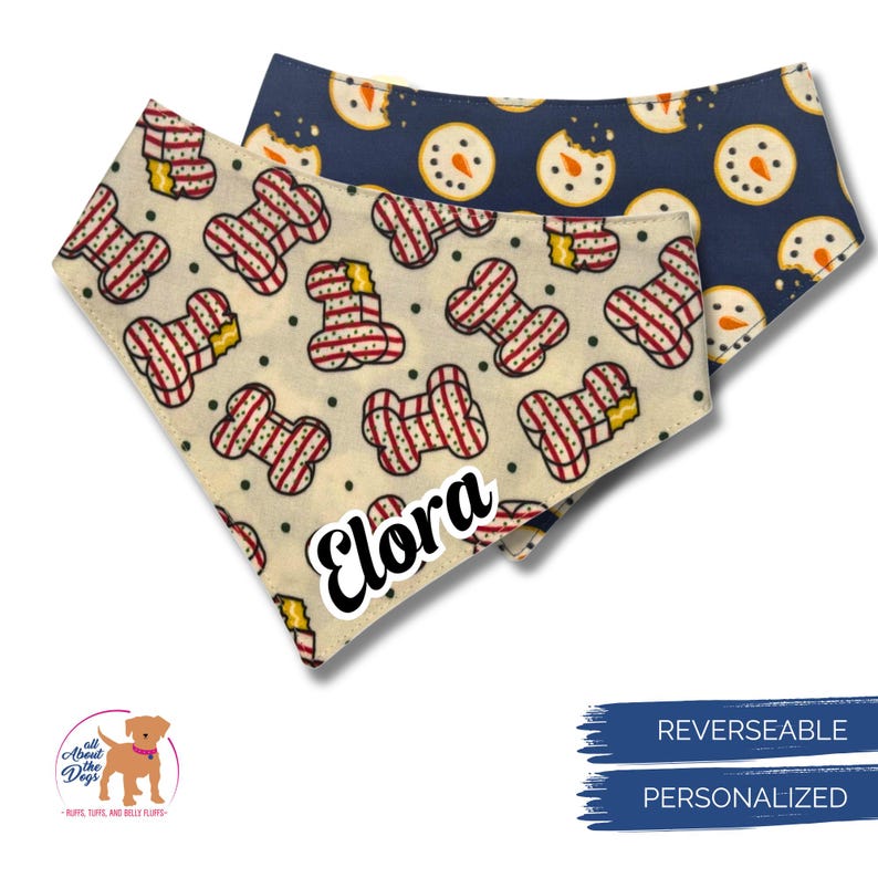 May include: Two reversible dog bandanas. One is cream-colored with red and white striped bone shapes and the name "Elora". The other is navy blue with snowman cookie designs. The bandanas are personalized.