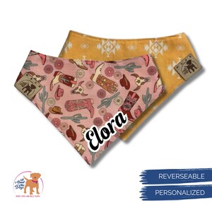 May include: Reversible dog bandana with a pink side featuring cowboy boots, hats, and cacti, and a yellow side with a geometric pattern. The name "Elora" is printed on the pink side. The bandana is personalized.