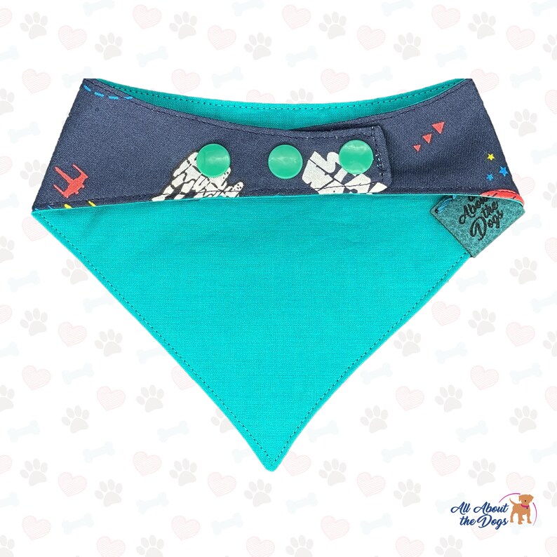 Pu&ograve; includere: Un bandana per cani blu turchese con un rovescio a fantasia blu navy e bianco. Il bandana ha tre chiusure a scatto e un'etichetta che dice "All About the Dogs".