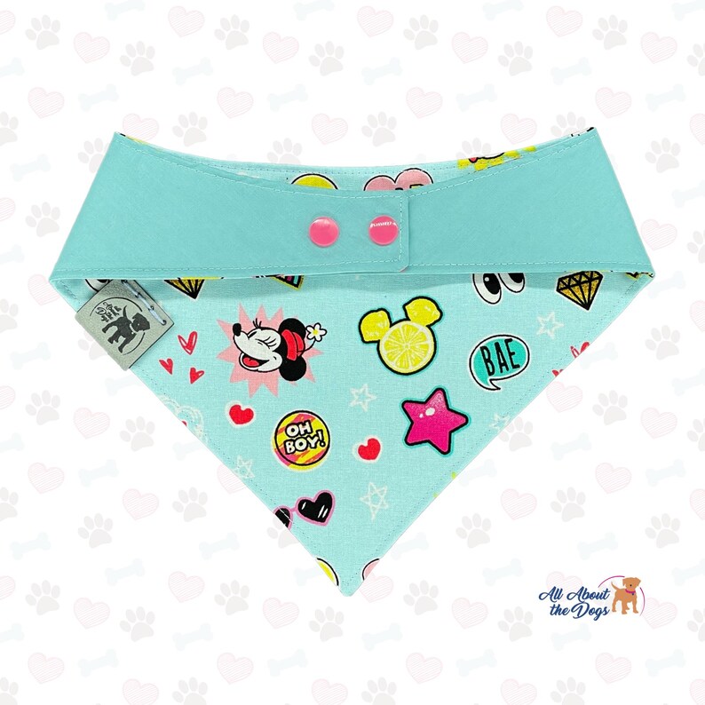 May include: A turquoise dog bandana featuring cartoon graphics of Minnie Mouse, hearts, stars, and the text "OH BOY!". The bandana has a turquoise collar with pink buttons and a tag that says "All About the Dogs".
