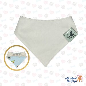 Peut inclure: Un bandana pour chien de couleur gris clair avec une petite &eacute;tiquette vert clair qui dit "All About the Dogs" et une petite silhouette noire d'un chien. Le bandana est pr&eacute;sent&eacute; sur un fond blanc avec un motif de c&oelig;urs roses, de pattes grises et d'os bleus.