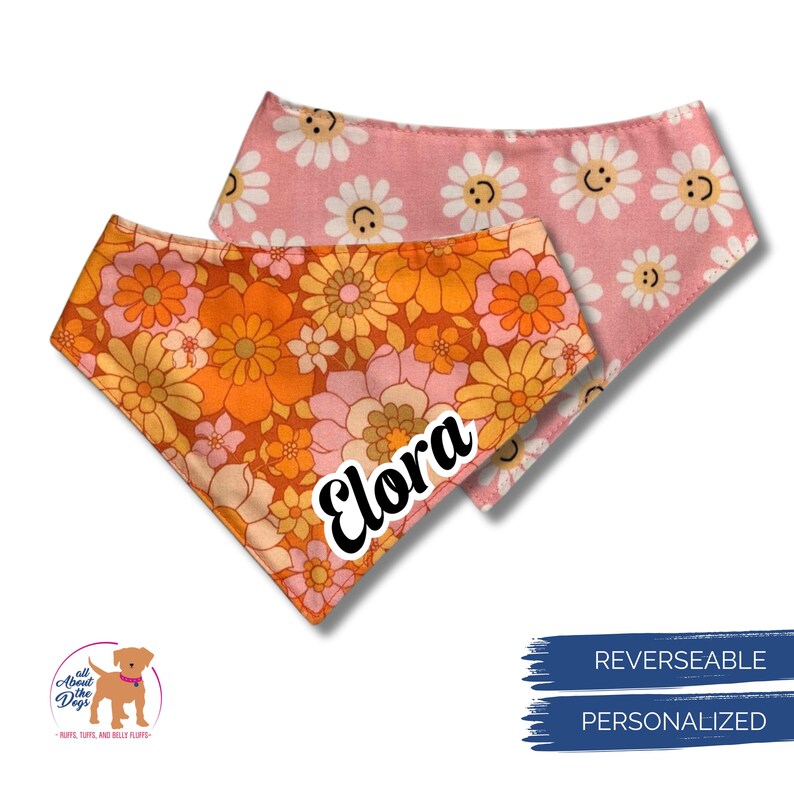 Puede incluir: Dos pa&ntilde;uelos reversibles para perros. Uno presenta un estampado floral en naranja, rosa y amarillo. El otro es rosa con margaritas blancas y caras sonrientes. El nombre "Elora" est&aacute; impreso en el pa&ntilde;uelo floral.
