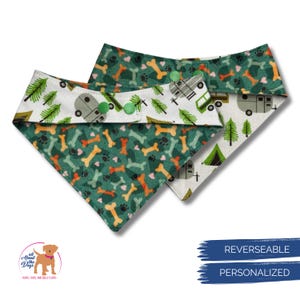 Op de afbeelding: Twee omkeerbare hondenbandana's. De ene kant heeft een groene achtergrond met oranje en gele botten en pootafdrukken. De andere kant heeft een witte achtergrond met groene bomen en een kampeerwagen. Groene knopen bevestigen de bandana.